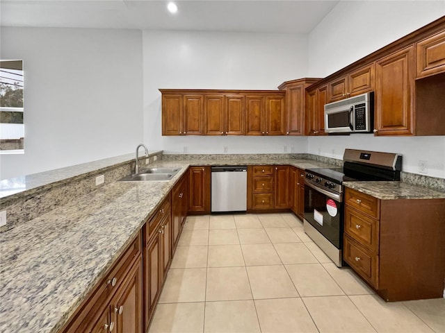 kitchen featuring stainless steel appliances, sink, light tile patterned floors, and light stone counters