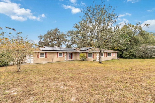 single story home featuring a front lawn and solar panels