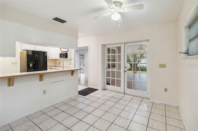 kitchen with french doors, a breakfast bar area, black refrigerator with ice dispenser, kitchen peninsula, and white cabinets