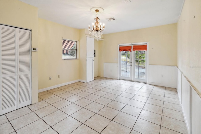 spare room with french doors, a chandelier, and light tile patterned floors