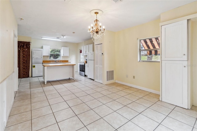 kitchen with light tile patterned flooring, stainless steel range with electric cooktop, white cabinetry, decorative light fixtures, and a notable chandelier