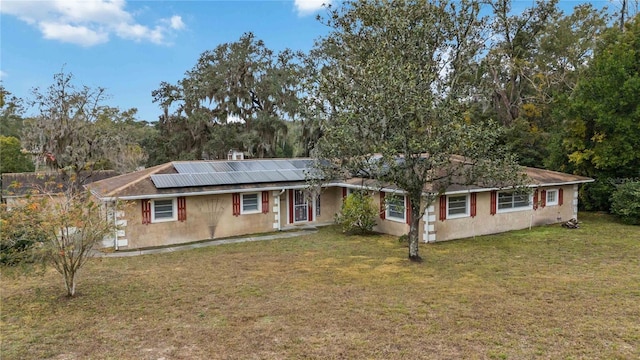 single story home featuring a front lawn and solar panels