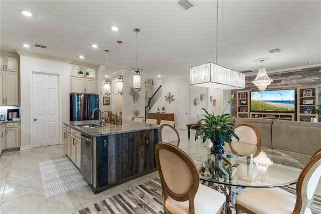 kitchen with a kitchen island with sink, hanging light fixtures, cream cabinets, and sink