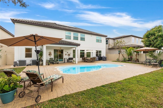 rear view of property featuring cooling unit, a fenced in pool, and a patio