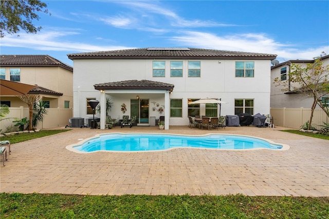 rear view of house with a fenced in pool, a patio, and solar panels