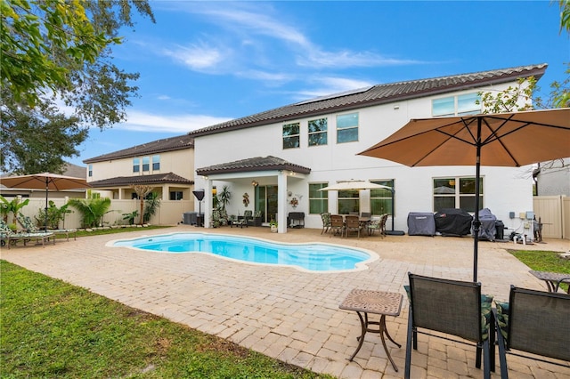 back of property featuring a fenced in pool and a patio