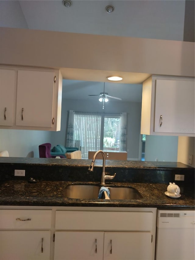 kitchen featuring white cabinetry, dark stone counters, white dishwasher, and sink