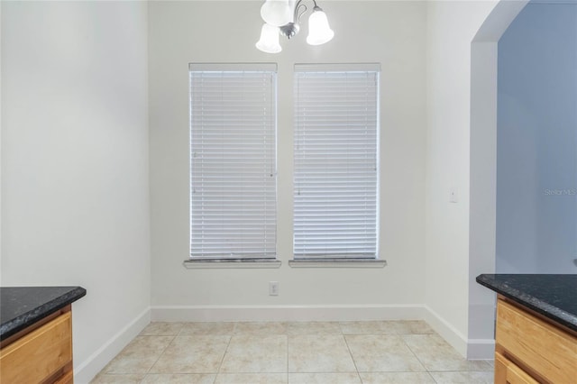 unfurnished dining area featuring an inviting chandelier and light tile patterned floors