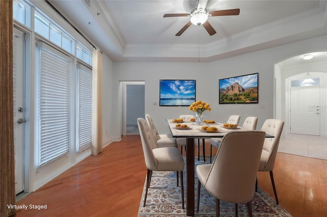 dining space featuring ornamental molding, a tray ceiling, light hardwood / wood-style flooring, and a wealth of natural light