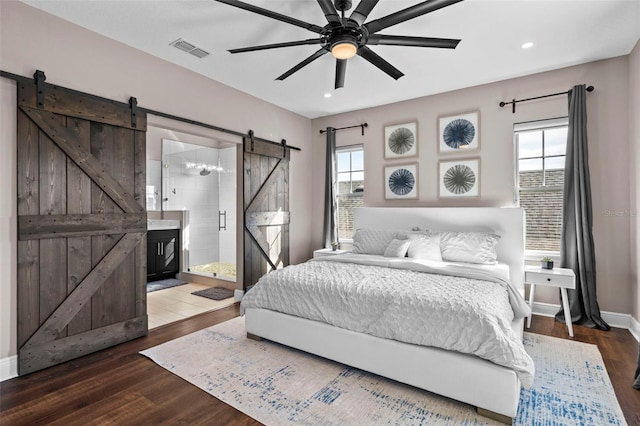 bedroom with ceiling fan, dark hardwood / wood-style flooring, ensuite bathroom, and a barn door