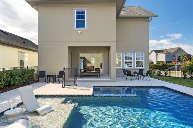 back of property with a swimming pool with hot tub and a patio