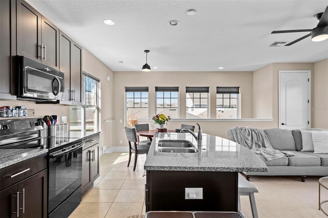 kitchen with sink, hanging light fixtures, electric range, a center island with sink, and dark brown cabinets