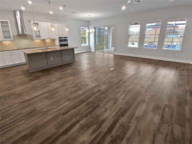 kitchen featuring a kitchen island with sink, extractor fan, dark hardwood / wood-style flooring, and white cabinets