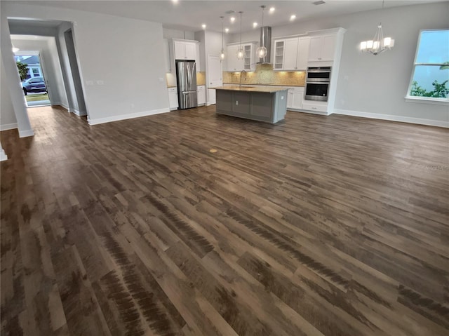 unfurnished living room with sink, dark hardwood / wood-style floors, and a chandelier