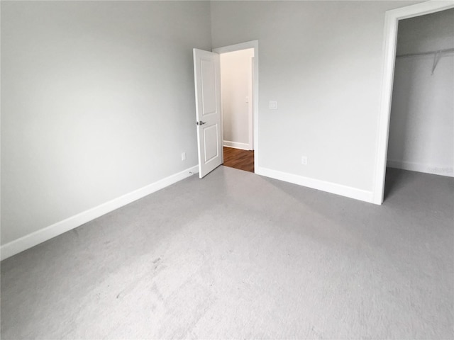 unfurnished bedroom with a walk in closet, dark carpet, and a closet