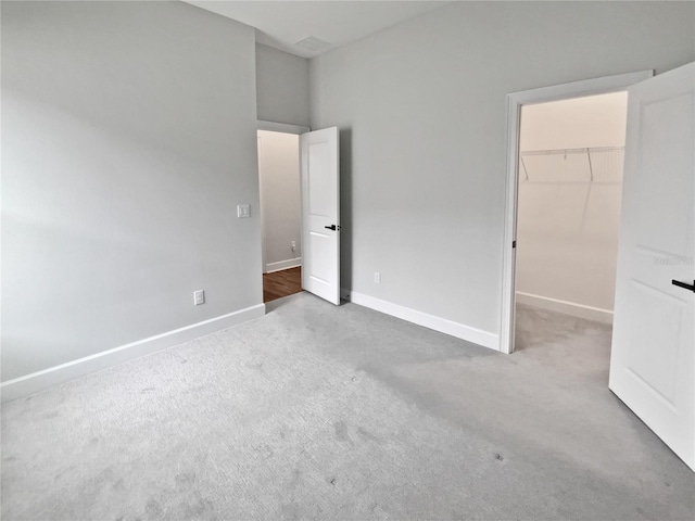 unfurnished bedroom with a walk in closet, a closet, and carpet flooring