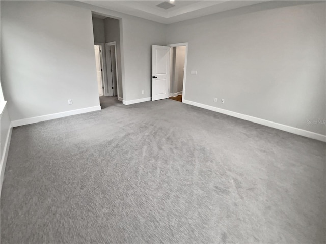 unfurnished room featuring a tray ceiling and dark colored carpet