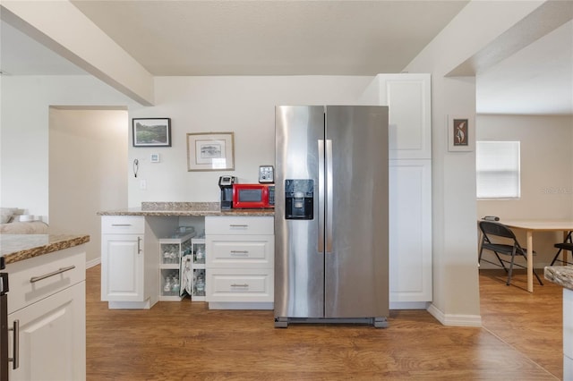 kitchen featuring wood-type flooring, light stone countertops, white cabinets, and stainless steel fridge with ice dispenser