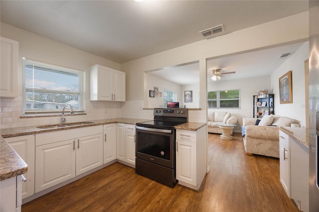 kitchen with sink, stainless steel electric range, white cabinetry, backsplash, and wood-type flooring