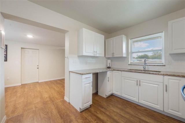 kitchen with backsplash, light hardwood / wood-style floors, sink, and white cabinets