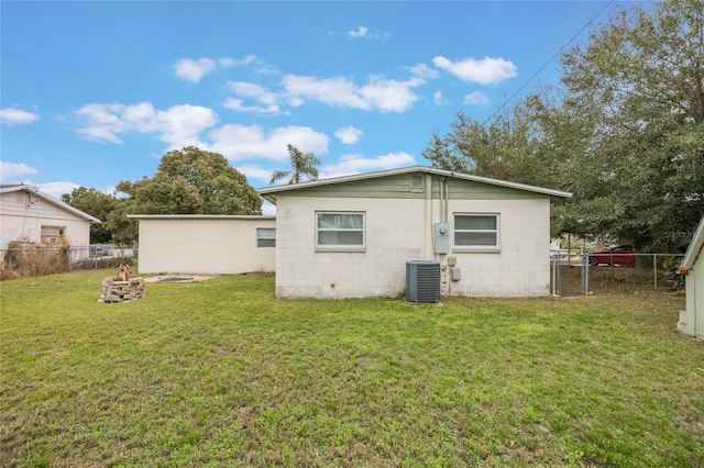 back of house with a yard, central AC unit, and a fire pit