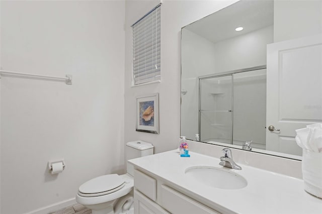 bathroom featuring vanity, a shower with shower door, and toilet