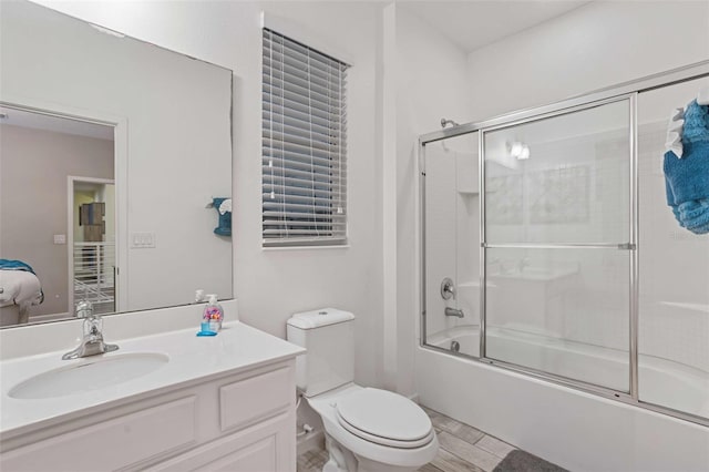 full bathroom with enclosed tub / shower combo, vanity, and toilet