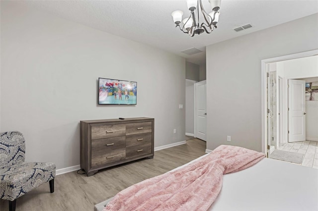 bedroom with an inviting chandelier, a textured ceiling, and light wood-type flooring