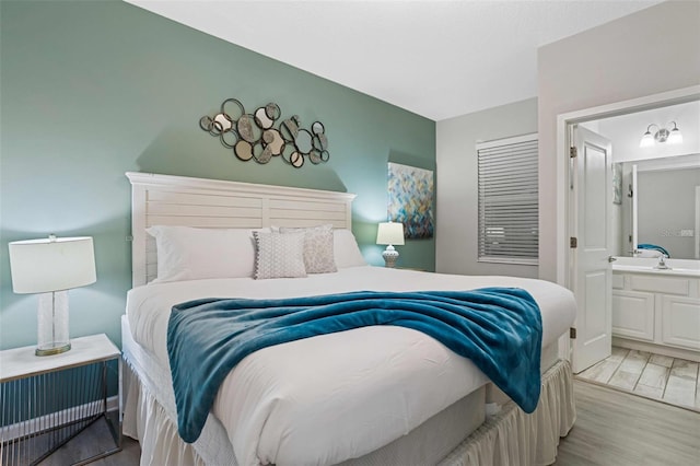 bedroom featuring sink, connected bathroom, and light hardwood / wood-style floors