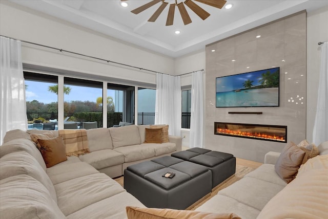 living room with a tiled fireplace, a towering ceiling, and ceiling fan