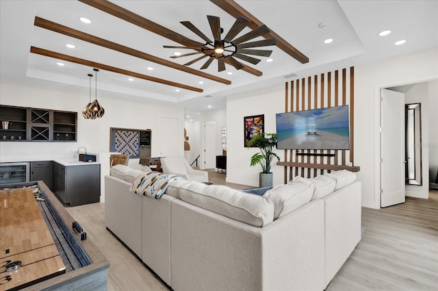 living room featuring a tray ceiling, bar area, beverage cooler, and light hardwood / wood-style floors