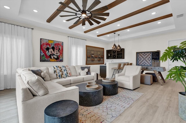 living room featuring light hardwood / wood-style floors, a raised ceiling, and a healthy amount of sunlight