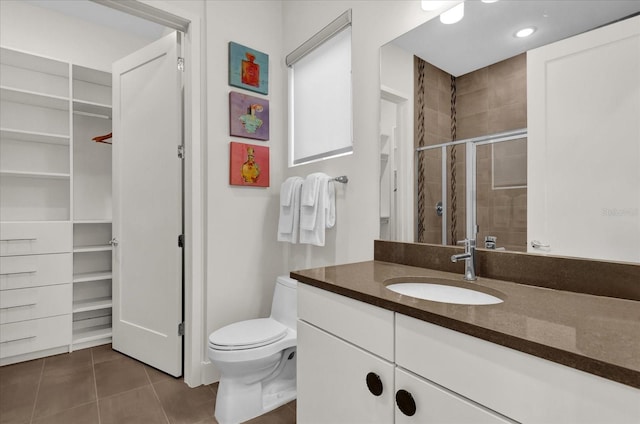 bathroom with walk in shower, vanity, toilet, and tile patterned flooring