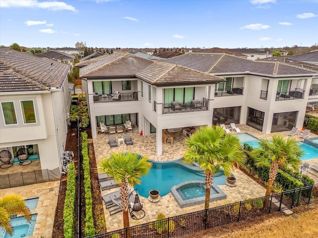 back of property with a swimming pool with hot tub and a patio