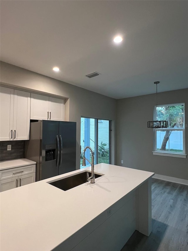 kitchen featuring sink, white cabinets, dark hardwood / wood-style flooring, stainless steel fridge with ice dispenser, and decorative light fixtures