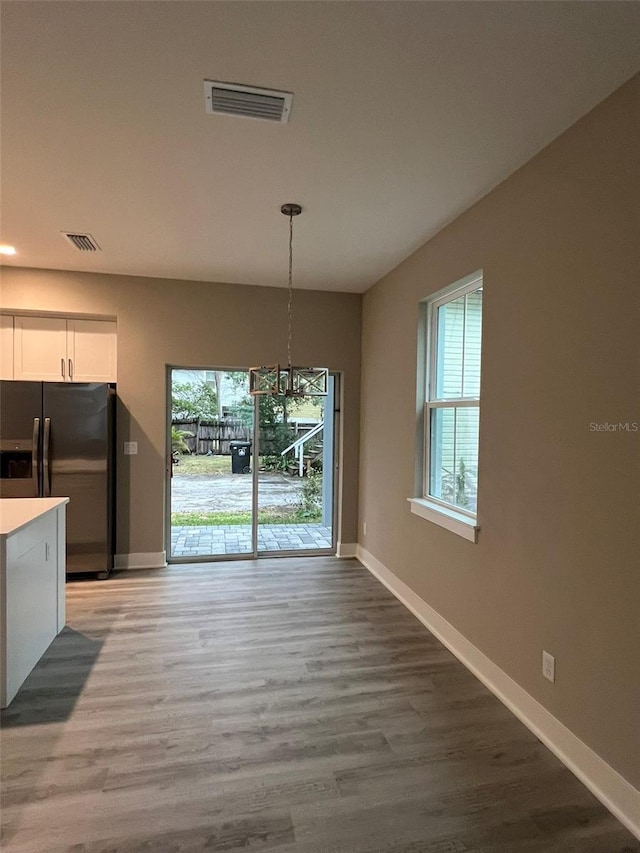 unfurnished dining area featuring wood-type flooring and a wealth of natural light