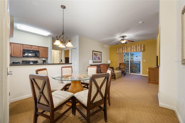 dining area featuring ceiling fan with notable chandelier and light colored carpet