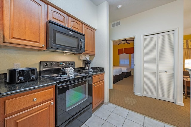 kitchen with black appliances, dark stone counters, and light tile patterned floors