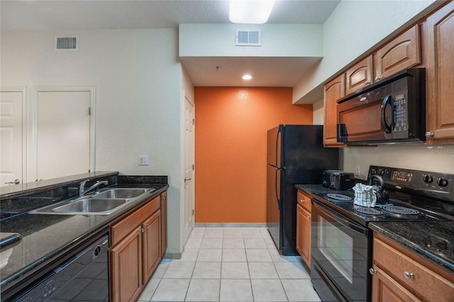 kitchen featuring sink, black appliances, light tile patterned floors, and dark stone countertops