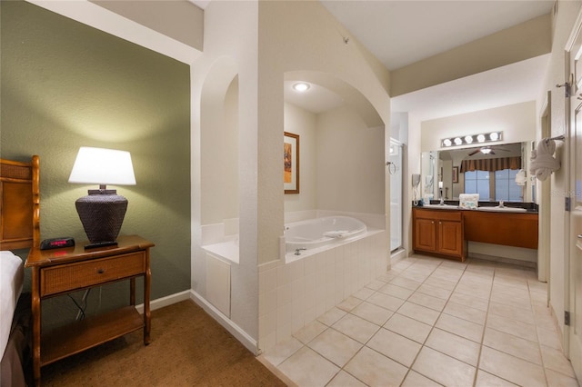 bathroom with a relaxing tiled tub, tile patterned floors, and vanity