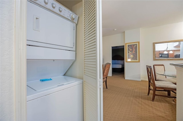 laundry room featuring light carpet and stacked washer / drying machine