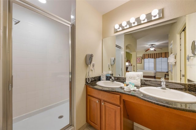 bathroom with a shower with shower door, vanity, and ceiling fan