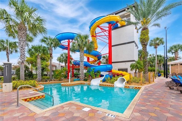pool featuring playground community, a water slide, and a patio area