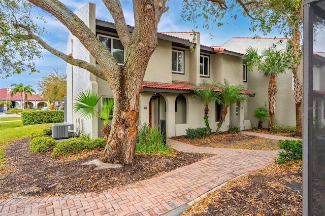 mediterranean / spanish home with central AC, a tile roof, and stucco siding