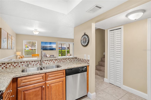 kitchen featuring light stone counters, light tile patterned flooring, a sink, visible vents, and dishwasher