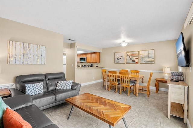 living room featuring light tile patterned floors, visible vents, and baseboards