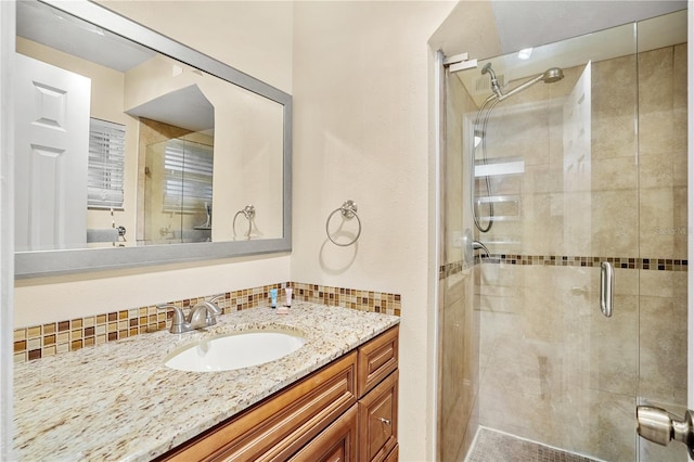full bathroom with a shower stall, tasteful backsplash, and vanity