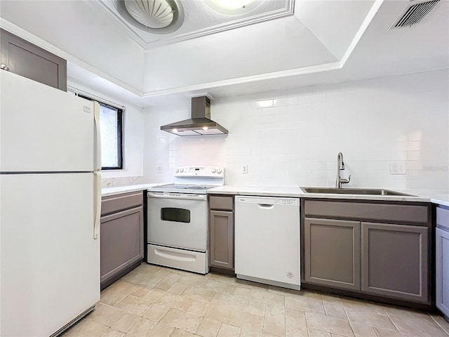 kitchen with a raised ceiling, sink, backsplash, exhaust hood, and white appliances