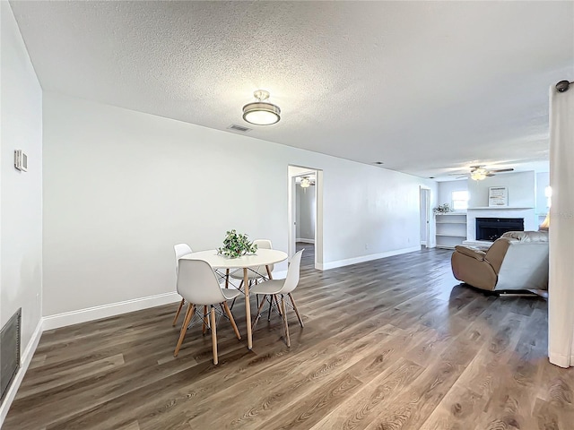 dining space featuring a textured ceiling, dark wood-type flooring, and ceiling fan