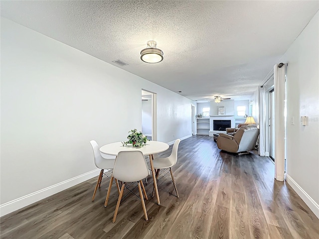 dining room with wood-type flooring, ceiling fan, and a textured ceiling